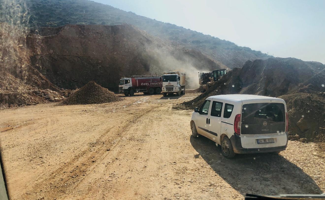 Hafriyat sahası; kamyonlar, iş makinesi ve kazı çalışması